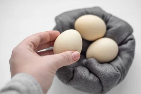 The female hand takes one egg from the basket of eggs. Stock Photos
