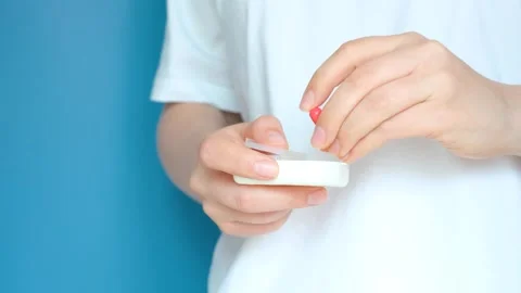 Female hand takes out capsule from pill box on a blue background. Stock Footage 246779234