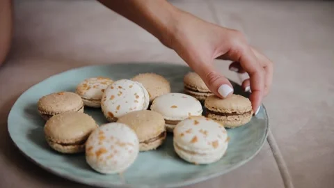 Female hand taking a one macaron filling with chocolate from big macaroons Stock Footage 234546570