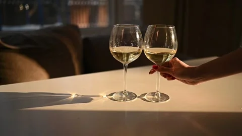 Female hand taking one of two glasses with dry white wine on white table Stock Footage 152521623