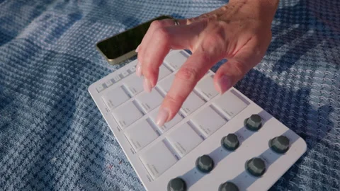 Female Hand Tapping Beats on Midi Pad Controller Beside Smartphone Outdoors Stock Footage 342771359