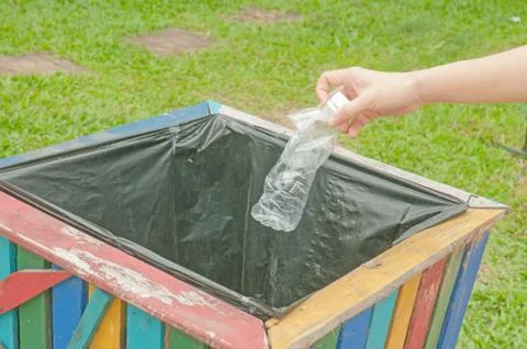 Female hand throwing empty plastic bottle into the trash. Stock Photos
