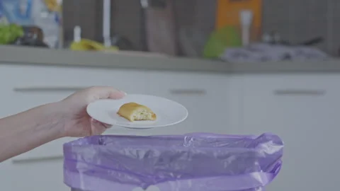 Female hand throws piece of baking from plate into trash bin Stock Footage 255499184