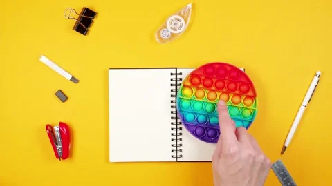 Female hand throws a white pen on a notepad and starts playing an anti-stress Stock Footage 165266764