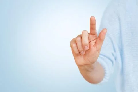 Female hand touching the virtual button with forefinger on blue background. Stock Photos