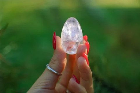 Female hand with transparent amethyst quartz yoni egg for vumfit, imbuilding or Stock Photos