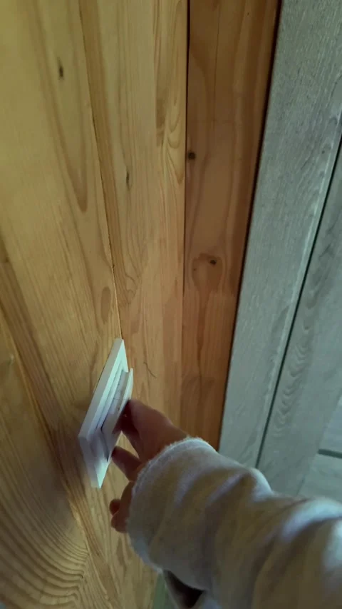 Female hand turning light switch on wooden wall inside cozy cabin house with Stock Footage 345726174