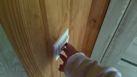 Female hand turning light switch on wooden wall inside cozy cabin house with Stock Footage 345731479