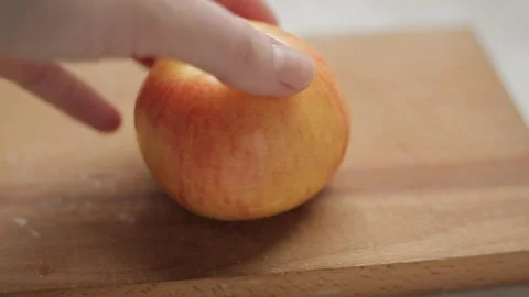 Female hand twists an apple on a cutting board Stock Footage