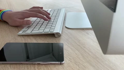 Female hand typing a computer. She's wearing a bracelet with lgtbi symbols. Stock Footage 131561526