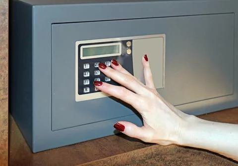 Female hand typing lockdown code on a hotel room safe Stock Photos