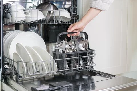 Female hand unloading dishwasher with tableware. Kitchen appliances, lifest.. Stock Photos