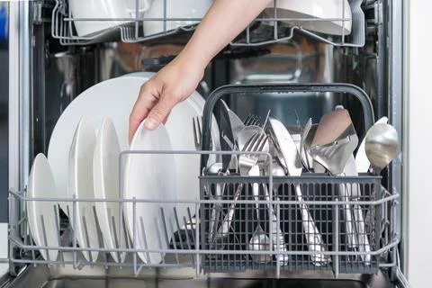 Female hand unloading dishwasher with tableware. Kitchen appliances, lifestyl Foto stock