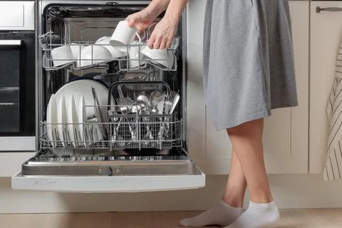 Female hand unloading dishwasher with tableware. Kitchen appliances, lifestyl Stock Photos