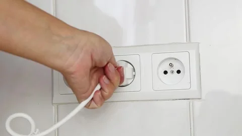 Female hand unplugging an electrical power plug from a wall socket. 스톡 동영상 339006787