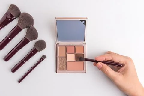 Female hand using brush on eyeshadow palette with mirror isolated on white .. Stock Photos