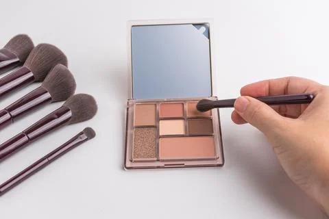 Female hand using brush on eyeshadow palette with mirror isolated on white .. Stock Photos