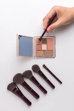 Female hand using brush on eyeshadow palette with mirror isolated on white .. Stock Photos