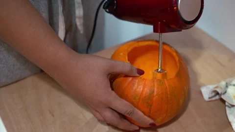 Female hand using electric beater to carve orange halloween pumpkin Stock Footage 278928983