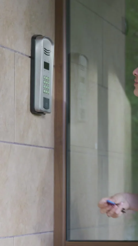 Female hand using a key fob to unlock a door entry system, showcasing the Stock Footage 341439346
