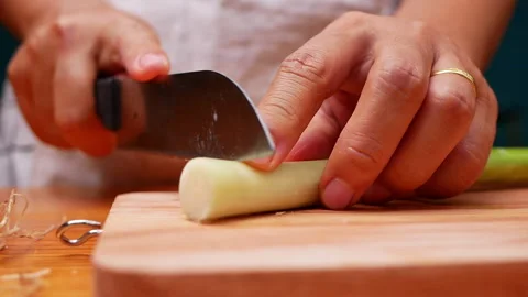 Female hand using kitchen knife to cut Japanese Scallion on wooden cutting board Vidéo 157085207