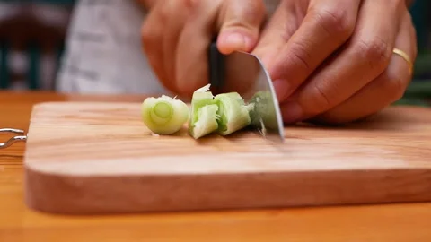 Female hand using kitchen knife to cut Japanese Scallion on wooden cutting board 動画素材 157085287