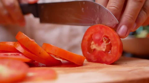 Female hand using kitchen knife to cut ripe tomato on wooden cutting board.  Stock Footage 157085412