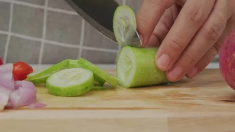 Female hand using a knife to slice cucumbers on a cutting board. Close-up. Stock Footage 243193443