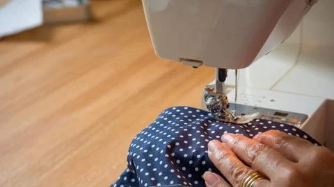 Female hand using sewing machine stitching fabic Stock Photos