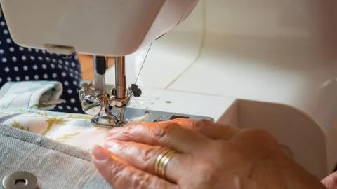 Female hand using sewing machine stitching fabic Stock Photos