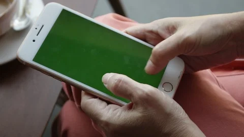 Female hand using a smartphone on green screen at the coffee shop. Video stock 107185871