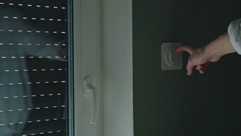 Female hand using switch to lift outdoor roller shutter indoors Stock Footage 332514804