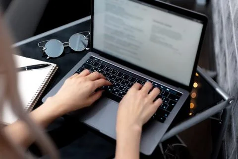 Female hand using touchpad of laptop. Black desk with sunglasses. Stock Photos