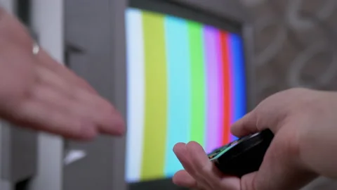 Female Hand Using TV Remote Control Tries a Switch SMPTE Color Bars Test Pattern Stock Footage 149378293