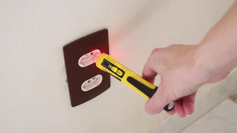 Female hand using a voltage tester pen to detect electricity in a wall socket. Video stock 321659882