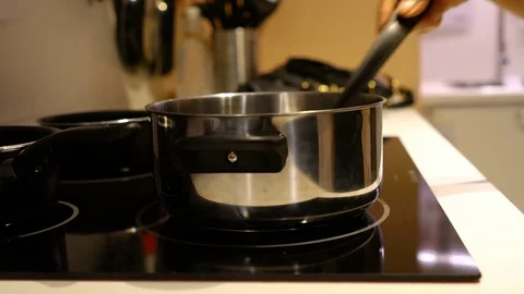 The female hand whisk for stirring in metal pot on the stove Stock Footage