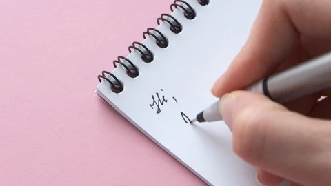 Female hand write letter begin word Dear Mr. on white notepaper on pink Stock Footage 129198626