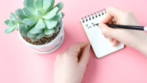 Female hand writes To Do List in notebook on pink background, planning concept. Stock Footage 236606840