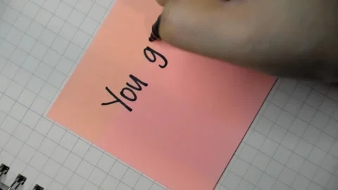Female hand writes down a message with black pen on a sticky note. Stock Footage 346005984