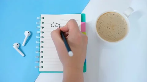 Female hand writes goals in notebook on white and blue background. Stock Footage 166183295