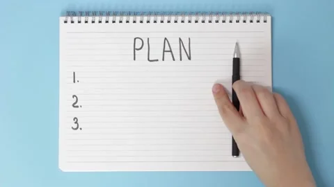 Female hand writes in notepad of goal for 2021 on blue background, top view Stock Footage 137487653
