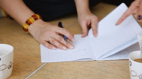 Female hand writes a pen in a notebook. Two girls Stock Footage 58163477