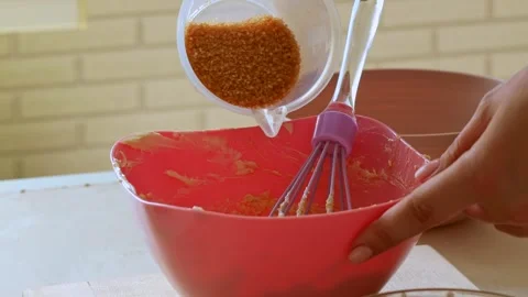 Female hands adding and mixing brown cane sugar with eggs and butter Stock Footage 297478193