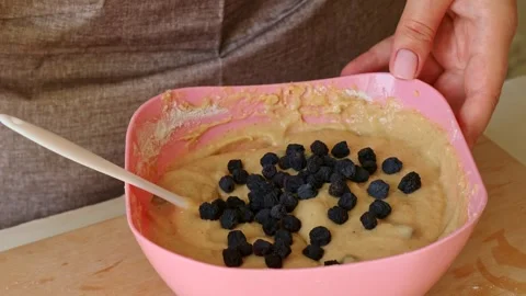 Female hands adding dried blueberries into dough for muffins and cookies Stock Footage 280856999