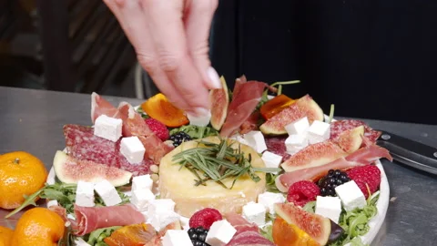 Female hands adding pine nuts to an appetizer with cheese, prosciutto, berries Stock Footage 145210229