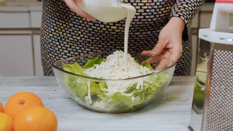 Female hands adding sauce to vegetable salad in her kitchen at home. Stock Footage 121660980