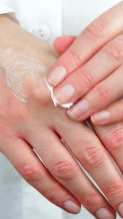 Female hands applying moisturizer to dry skin in close-up. Hand care routine Stock Footage 344523156