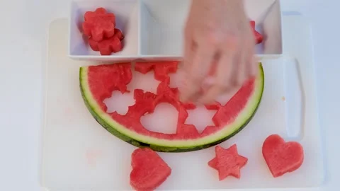 Female hands are cutting slice in heart, flower, star shapes of ripe watermelon. Stock Footage 243991791