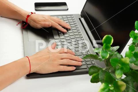 Female hands are typing text on laptop keyboard on white table background Stock Photos