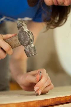 Female hands are using claw hammer and nail for making wooden bench, gender Foto stock